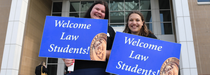 students holding up welcome law students signs. 