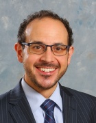 formal photo of a man wearing business suit and glasses, smiling. 