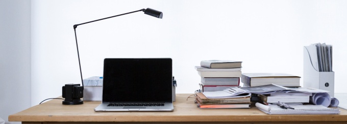 photo of a desk with a lamp and laptop and several books. 