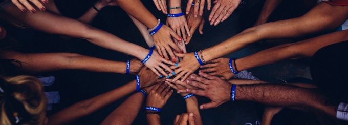 photo of multiple hands together in a huddle. 