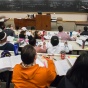 a view of a classroom with students taken from behind looking towards the chalkboard and professor. 