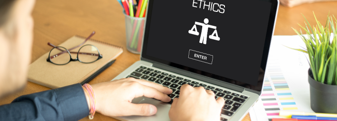 man with fingers on laptop keyboard, the screen shows the word Ethics. 