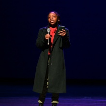 woman on a stage holding a microphone. 