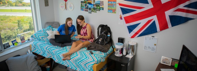 Two students use a laptop together in a residence hall room. 
