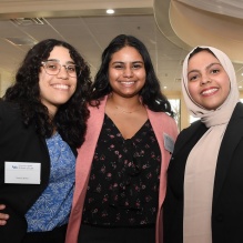 three students standing together, smiling. 