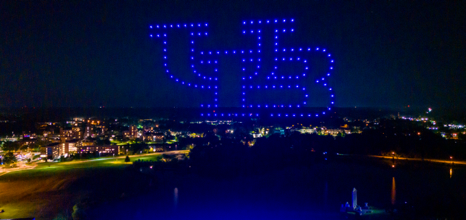 night lights spelling the letters UB up in the sky above campus. 
