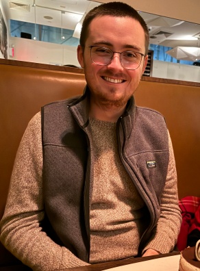 photo of tim sitting outside on a bench. 