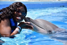 Jéla in a pool being "kissed" by a dolphin. 