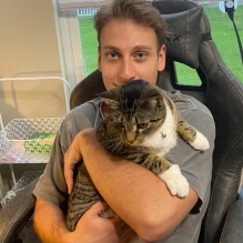 Jon sitting in a chair holding a cat. 