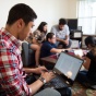 Students gathered in an apartment looking at a laptop. 