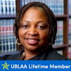 woman, smiling, in a library. text underneath says UBLAA Lifetime Member. 