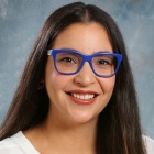 woman, smiling, wearing glasses with blue frames. 