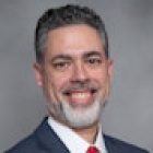 man, smiling, wearing business suit with a red tie. 