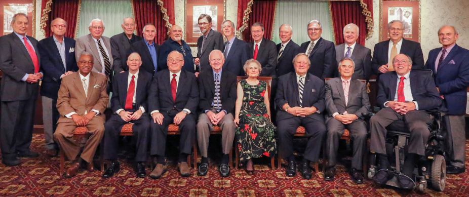 group of alumni inside a large room, posing for their grup photo. 