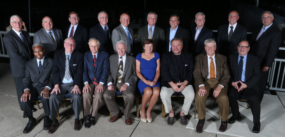 group of alumni sitting outside at night, posing for their group photo. 