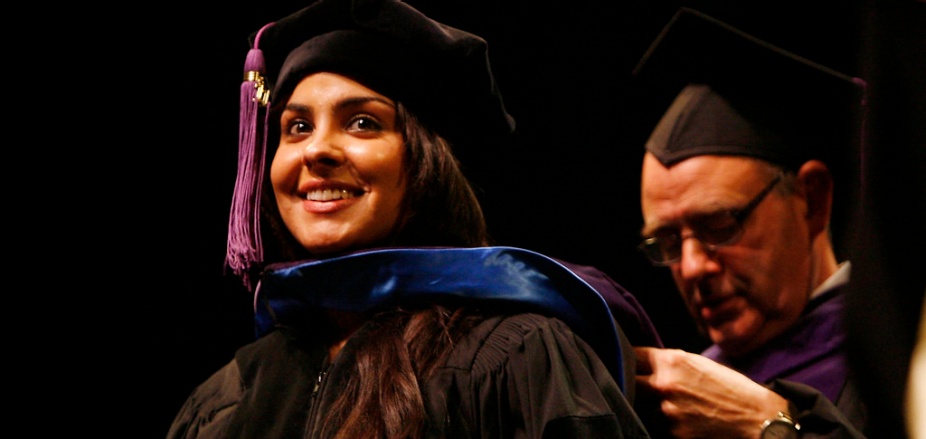 photo of graduate getting hooded during their commencement ceremony. 