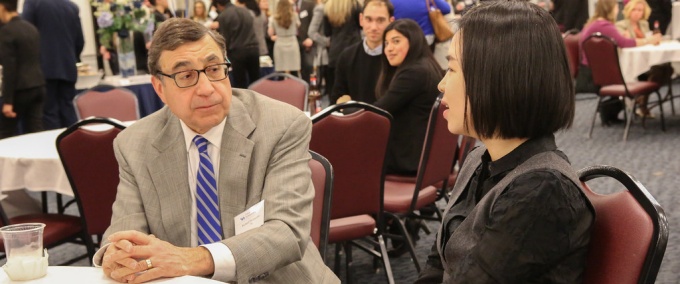 mentor listening to a student at a reception. 