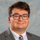 man wearing glasses, smiling. 