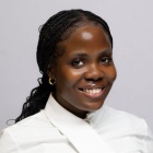Mena Arhere smiling, wearing a white shirt. 