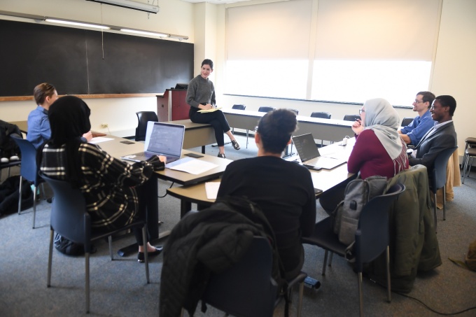 students in a classroom with professor harrington sitting in the center of the room. 