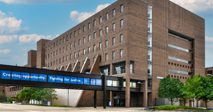 Exterior image of O'Brian Hall, North Campus with the bridge text "Creating opportunity. Fighting for justice". 