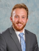 formal photo of a man wearing business suit and glasses, smiling. 