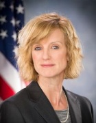 Barnes sitting, U.S. flag behind her. 