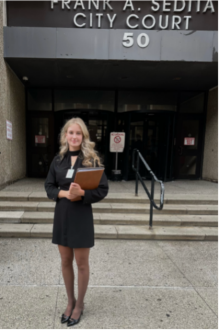 Young woman standing in front of a court house. 