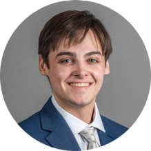 young man wearing a suit and tie, smiling. 
