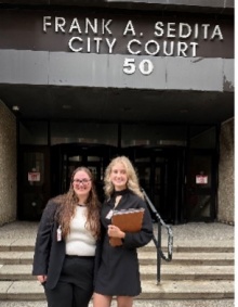 Two young women standing outside in front of a city courthouse.