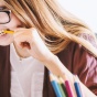 woman looking at a laptop nervously biting on a pencil. 