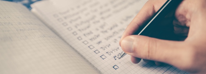 person writing check list on book. 