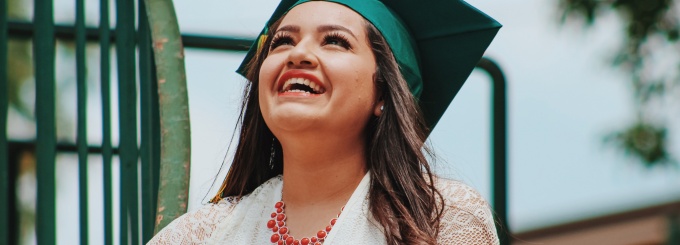 close up photo of a woman wearing a green academic mortar board. 
