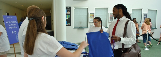 Picture of two new law students at orientation registration table being helped by two current law students. 