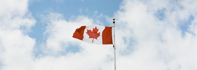 The Canadian flag waiving with the sky in the background. 