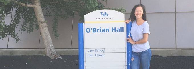Christina Cottone standing next to the O'Brian Hall sign on a campus tour. 