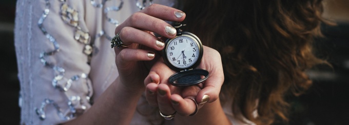 Woman holding a small clock. 