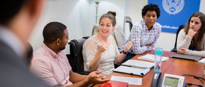 four university at buffalo law students sit at a conference table having a discussion. 