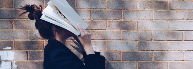 woman covering her face with white book. 
