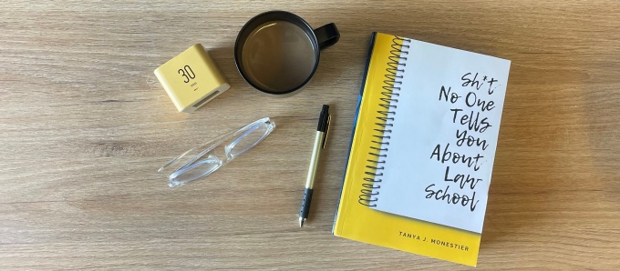 Table with the book Sh*t No One Tells You About Law School, glasses, a coffee cup, and glasses. 