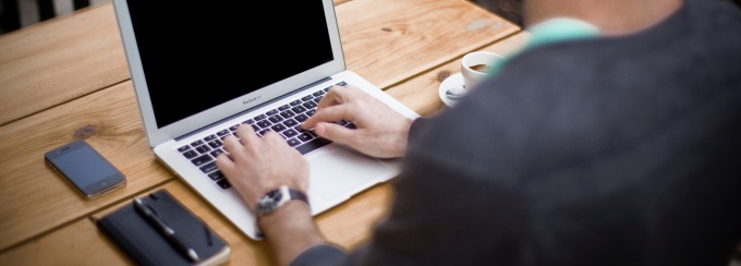 photo of a a person writing in a notebook sitting outside.