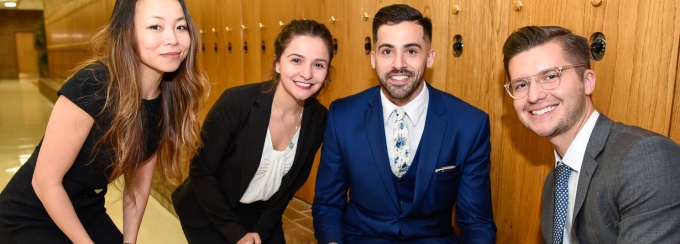 Picture of four upper-level law students dressed professionally in school hallway. 