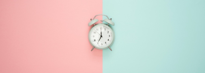 a clock in the middle with half of the background blue and the other half pink. 