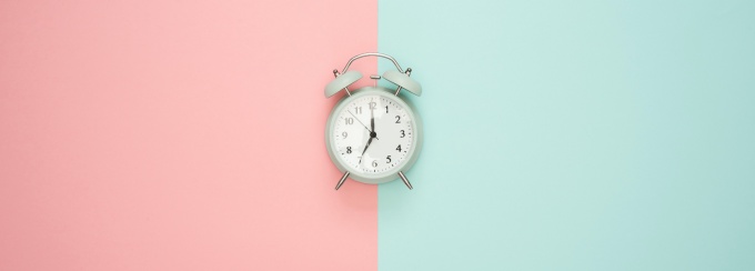 a clock in the middle with half of the background blue and the other half pink.