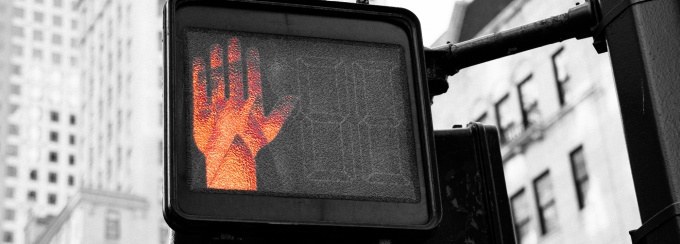 a hand signaling stop on a crosswalk sign. 