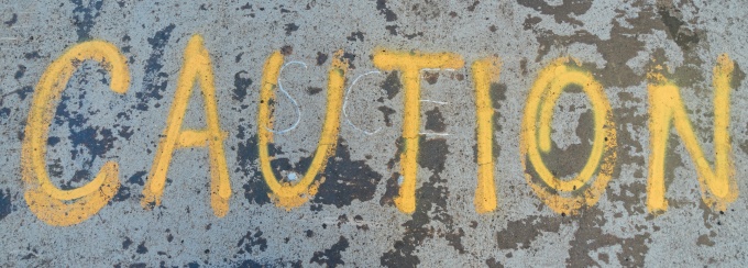 Photo looking down at the word caution spray painted on the pavement. 