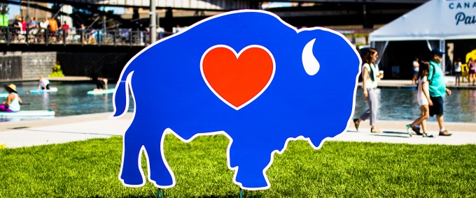 photo of blue buffalo with red heart sign in front of buffalo, new york's canal side harbor. 