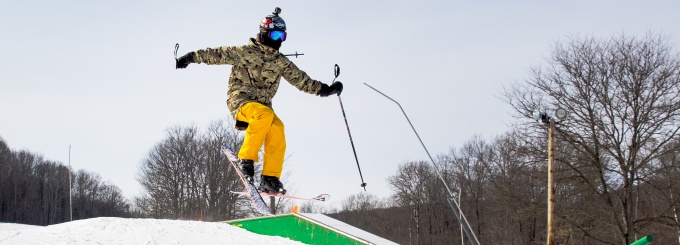 Skiier jumping onto rail. 