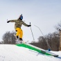 Skiier jumping onto rail. 