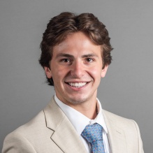 young man wering blue tie, smiling. 